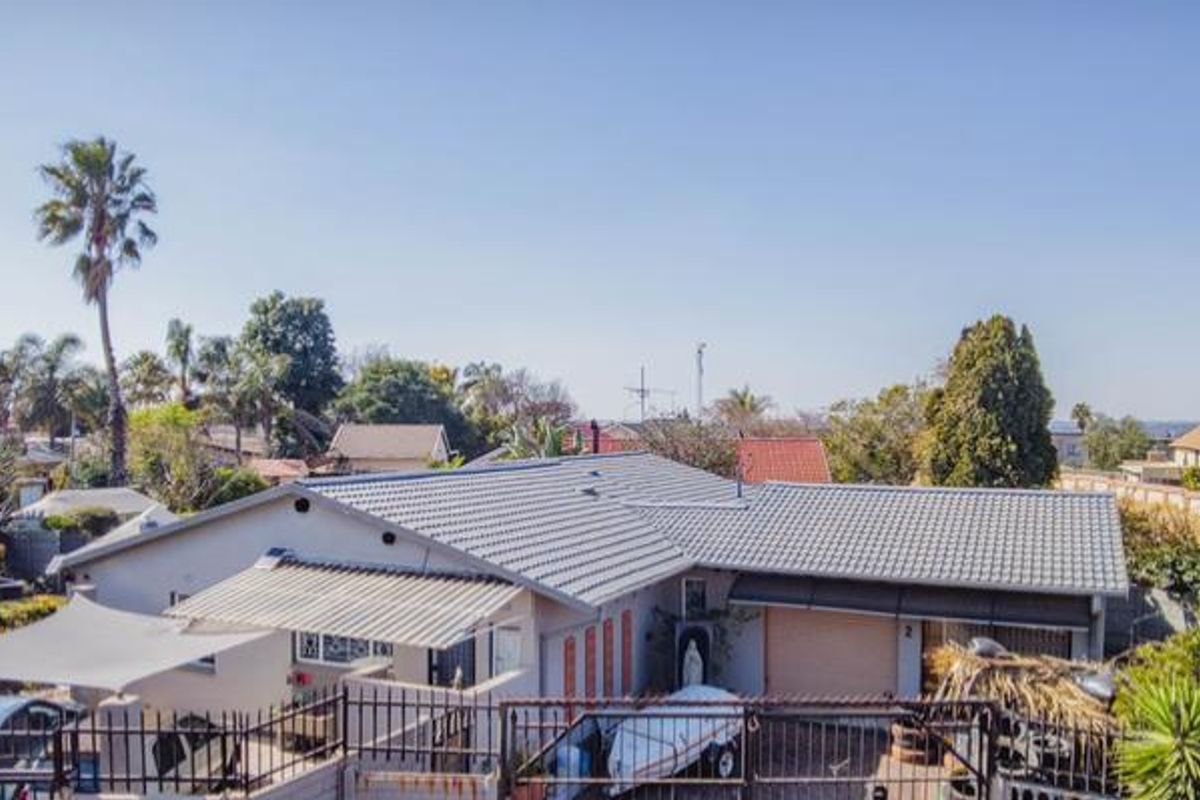 Aerial view of the property showing the main house structure, tiled roof, garage, and surrounding residential garden area.