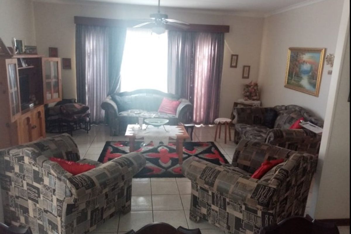 A spacious living room featuring tiled flooring, a ceiling fan, and coved cornicing, offering a functional layout for comfortable family living.