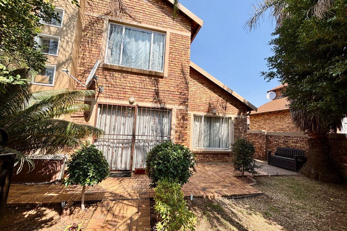 Rear view of a face brick house featuring a paved patio area, established garden, and secure access points.