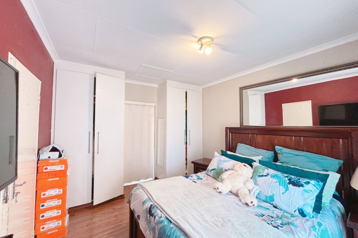A bedroom featuring built-in cupboards, laminate flooring, and a ceiling-mounted light fixture, providing functional storage and a neutral base for interior design.