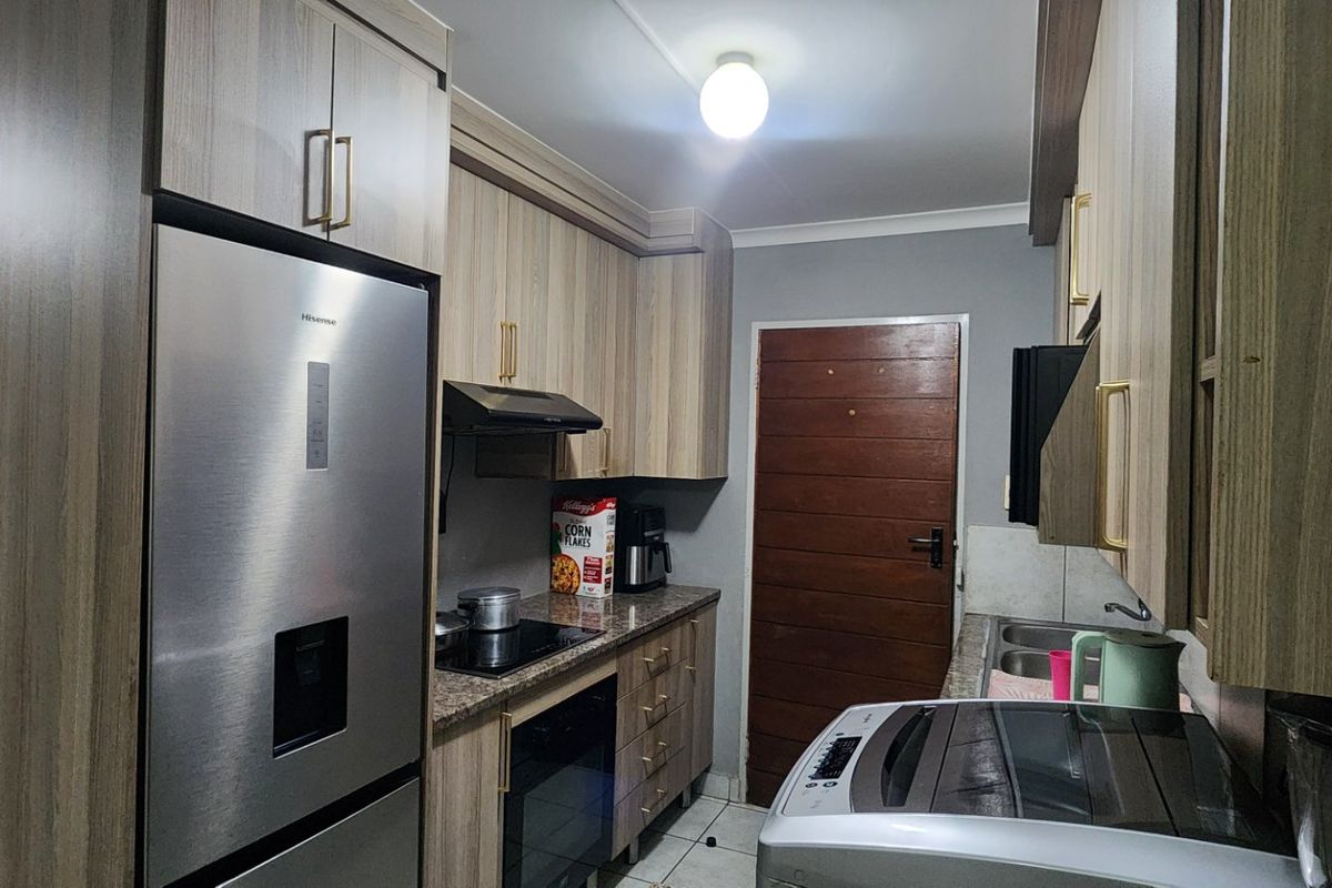 A functional kitchen featuring wood-look cabinetry, granite countertops, integrated appliances, and a double basin sink.