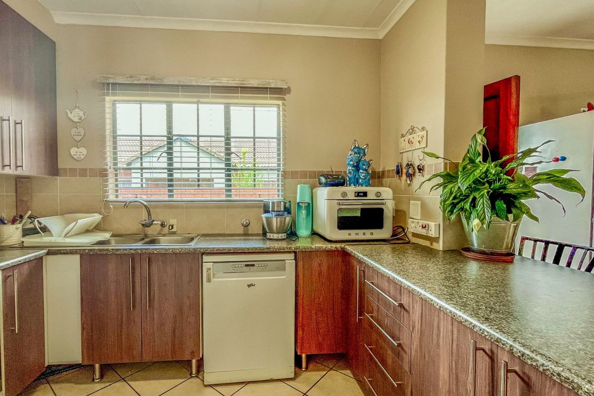 A functional kitchen featuring laminate cabinetry, granite countertops, a stainless steel double sink, and tiled flooring with a window providing natural light.
