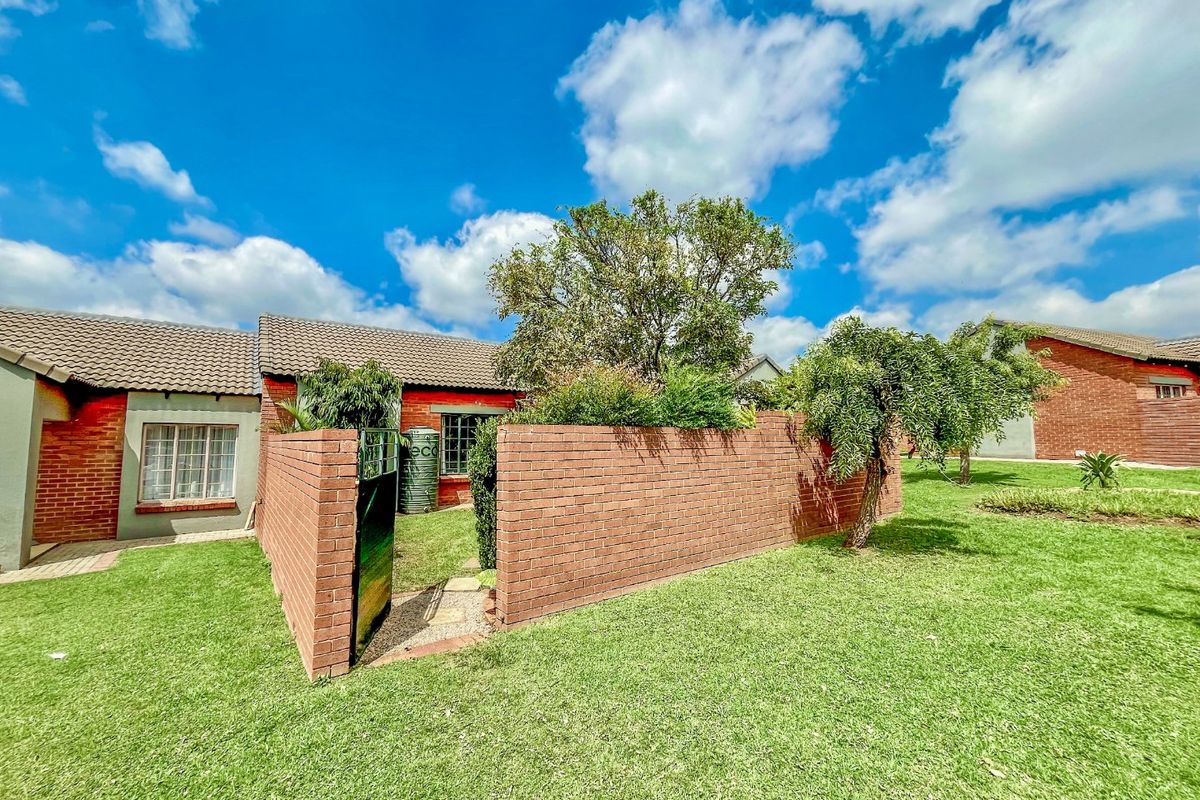 A view of the rear exterior featuring a brick boundary wall, tiled roof, and a private garden area with a water tank.