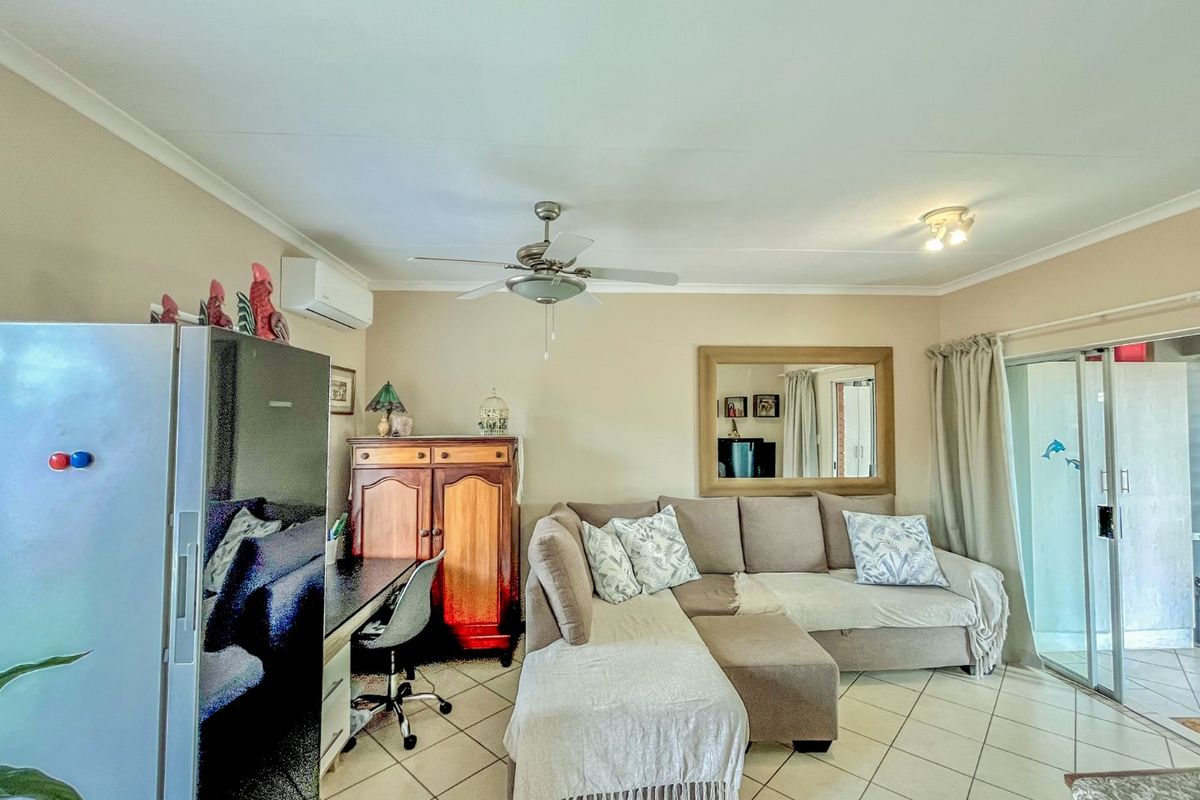 A living room featuring tiled flooring, a ceiling fan, and a split-system air conditioner, with direct access to an outdoor area via sliding glass doors.
