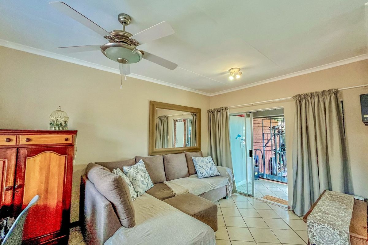 A living room featuring tiled flooring, a ceiling fan, and sliding glass doors providing access to an outdoor patio area.