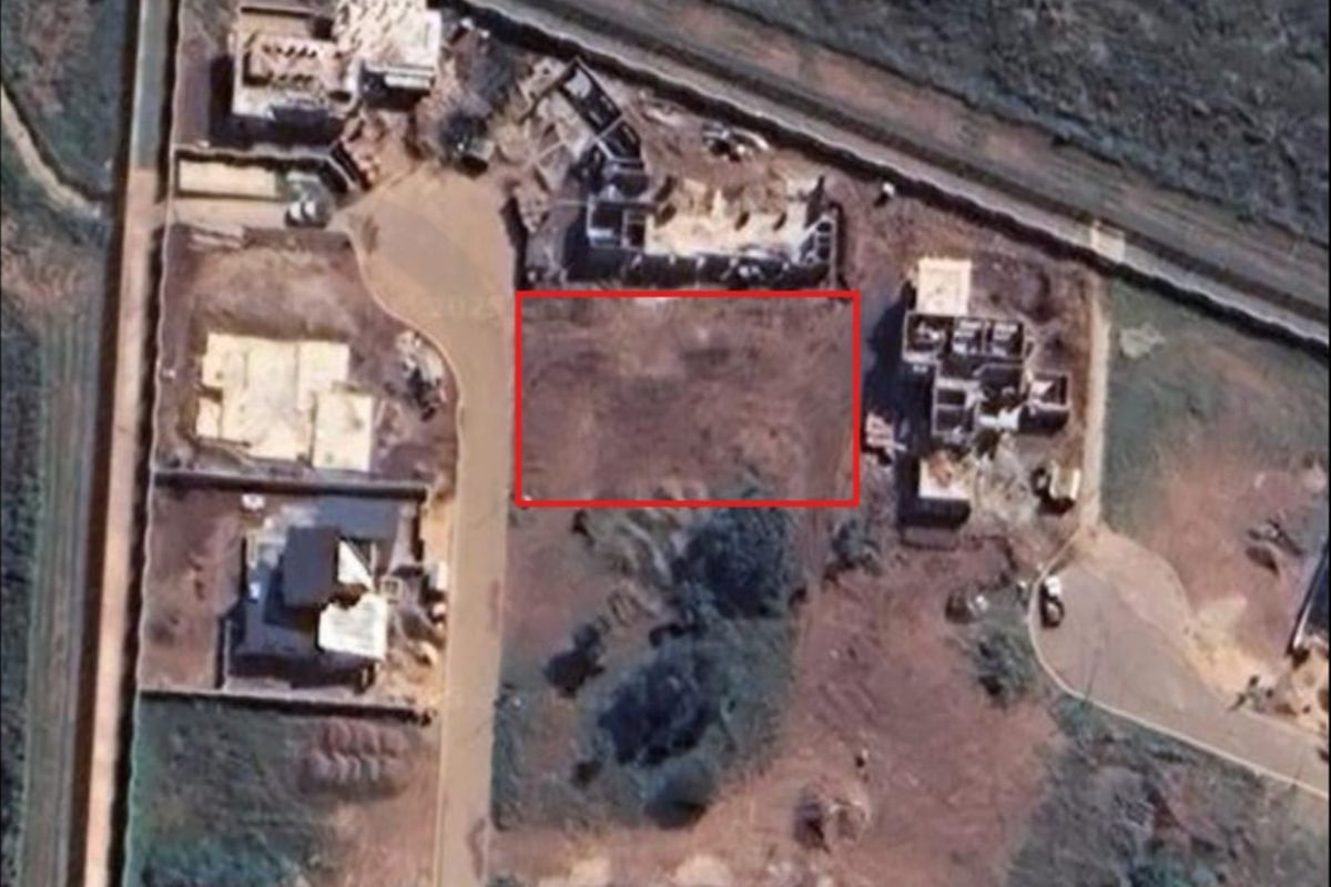 Aerial view of a vacant residential plot within a developing estate, showing surrounding construction activity and site boundaries.