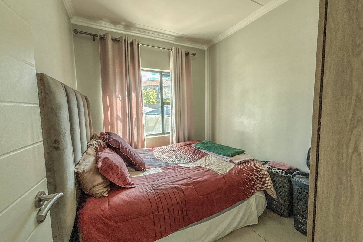 A compact bedroom featuring tiled flooring, neutral wall finishes, and a window allowing natural light.