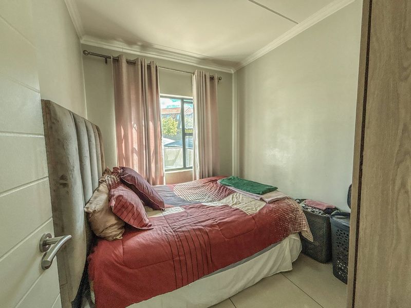 A compact bedroom featuring tiled flooring, neutral wall finishes, and a window allowing natural light.