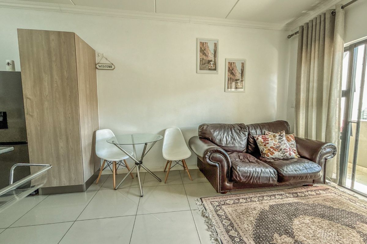 A bright living area featuring neutral tiled flooring and a sliding glass door providing access to the balcony.