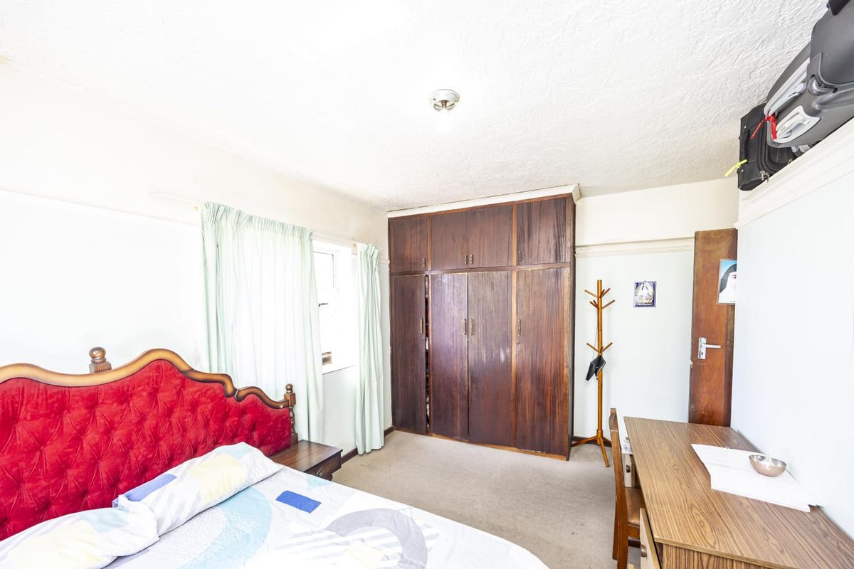 A bedroom featuring built-in wooden cupboards, carpeted flooring, and a ceiling light fixture.