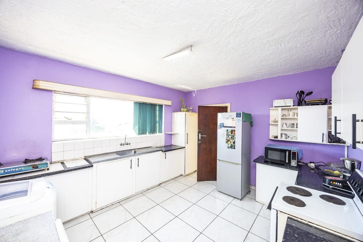 A functional kitchen featuring tiled flooring, built-in cabinetry, a stainless steel sink, and an electric stove, offering potential for modernization.
