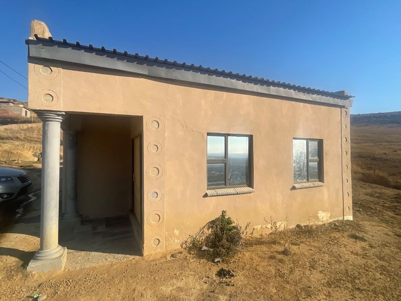 A single-story residential structure featuring plastered walls, aluminium window frames, and a covered entrance with a decorative column.