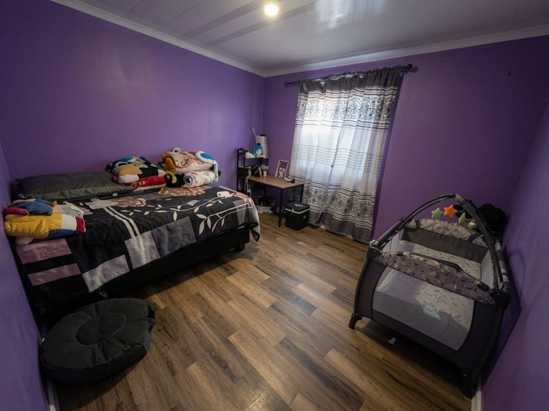A bedroom featuring laminate flooring and purple painted walls, providing a functional space with standard finishes.