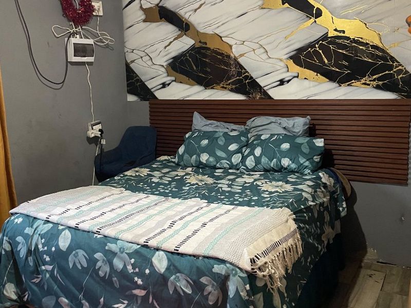Bedroom featuring wood-look tile flooring, a decorative marble-effect wall panel, and a slatted wood headboard feature, requiring some cosmetic attention to finishes.