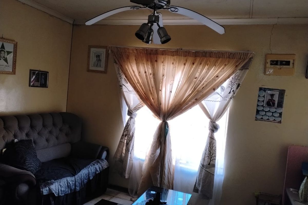 A living room featuring a ceiling fan and visible wall cracks, requiring maintenance and cosmetic updates to improve the overall aesthetic.