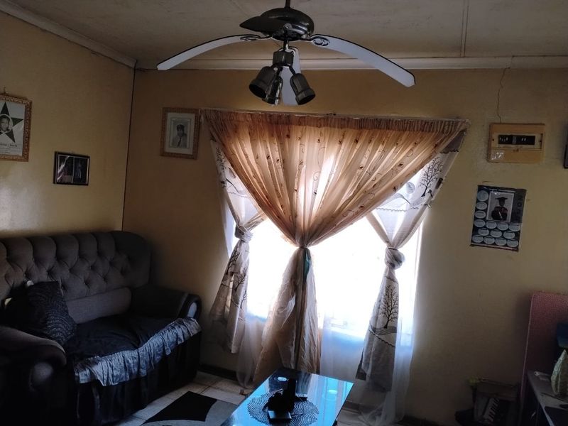 A living room featuring a ceiling fan and visible wall cracks, requiring maintenance and cosmetic updates to improve the overall aesthetic.
