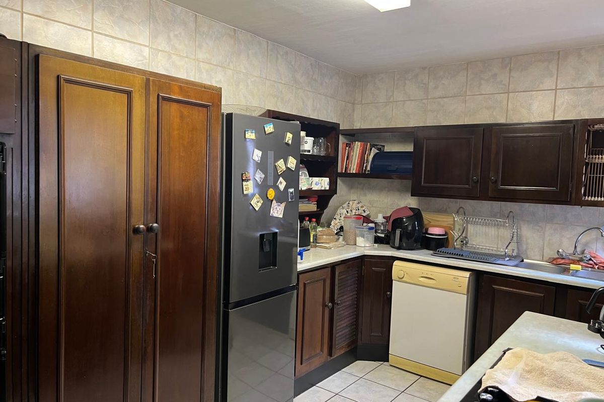 A functional kitchen featuring dark wood cabinetry, tiled backsplash, and tiled flooring, offering a traditional layout with ample storage space.