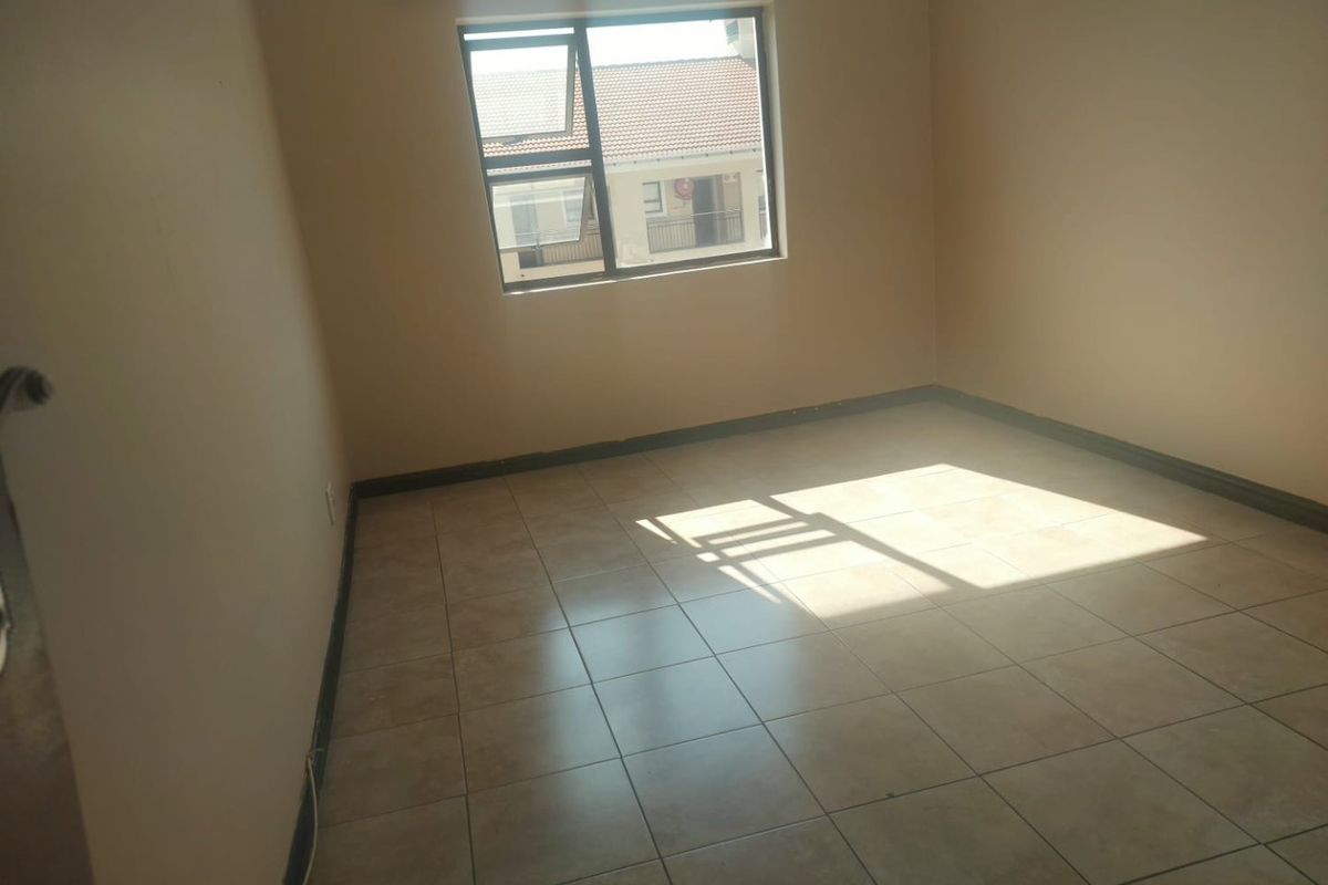 A vacant bedroom featuring neutral tiled flooring and a single aluminium-framed window, offering a blank canvas for interior design.