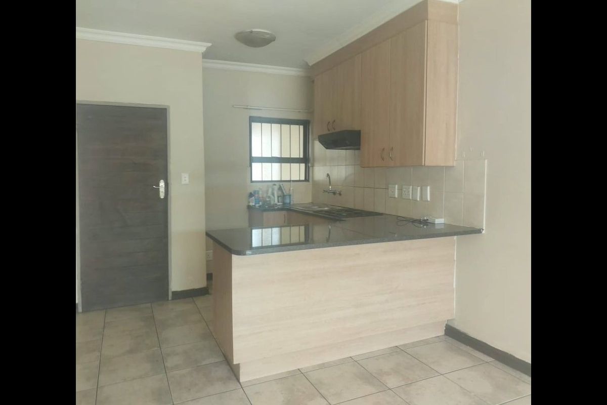 A functional kitchen featuring light wood cabinetry, granite countertops, a tiled backsplash, and tiled flooring, offering a clean and practical layout.