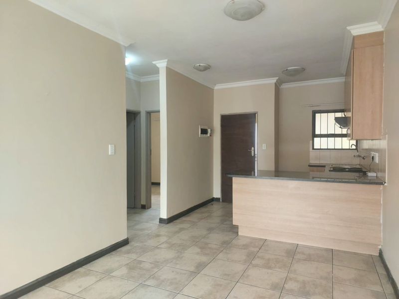 Open plan living area featuring tiled floors, neutral walls, and a functional kitchen with granite countertops, built-in cabinetry, and a hob.