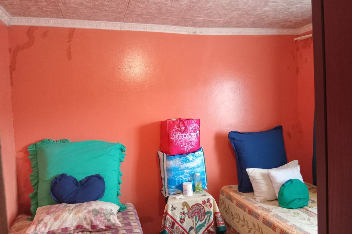 A bedroom featuring decorative ceiling tiles and coving, currently showing visible water staining on the walls.