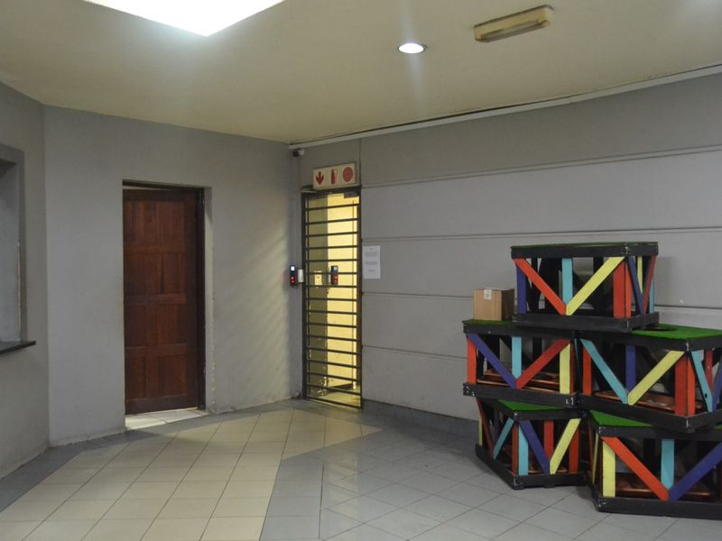 A functional apartment entrance area featuring tiled flooring, recessed lighting, and a secure metal gate.