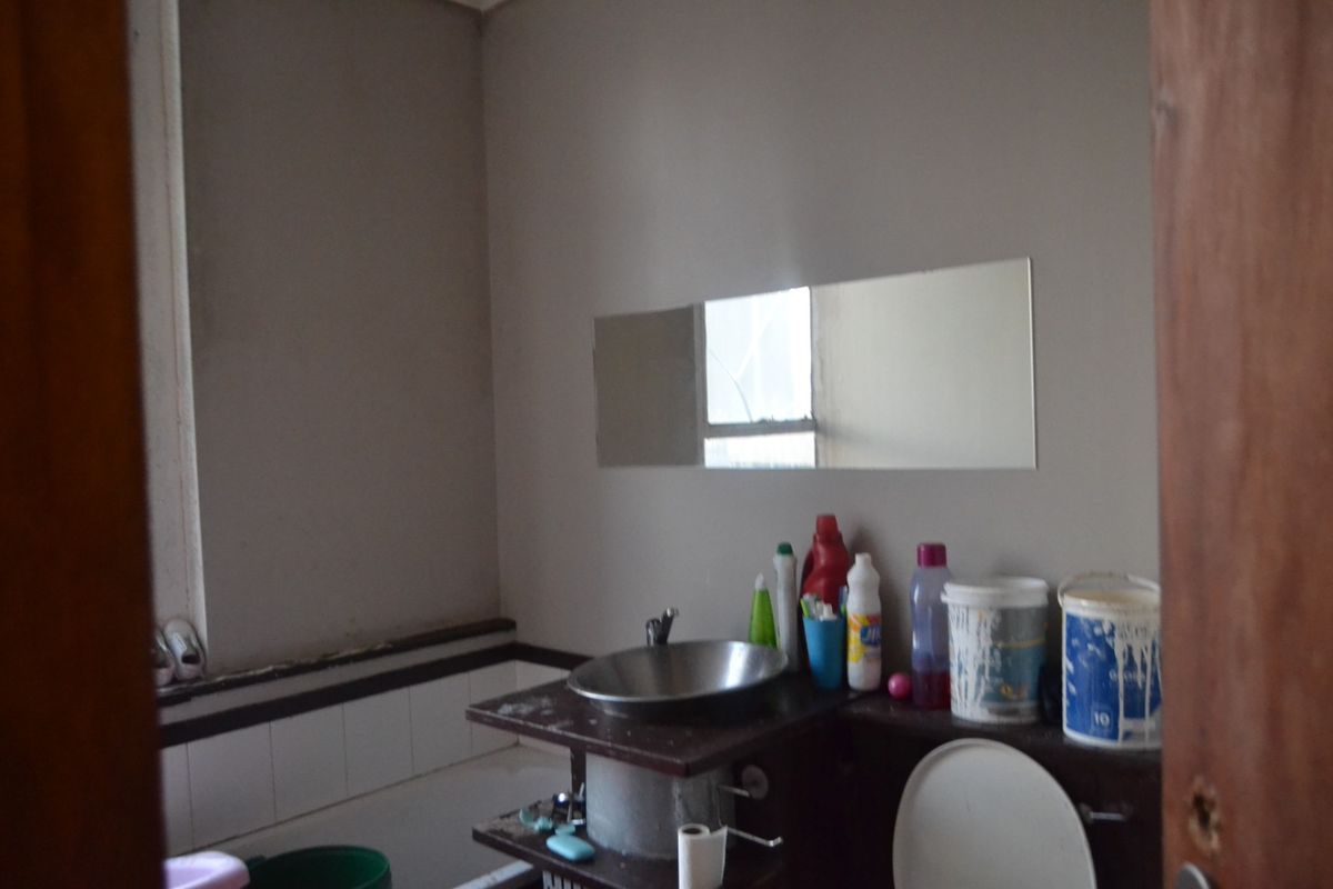 A dated bathroom featuring a basin, bathtub, and wall-mounted mirror, requiring renovation and cosmetic updates to improve its overall condition and functionality.