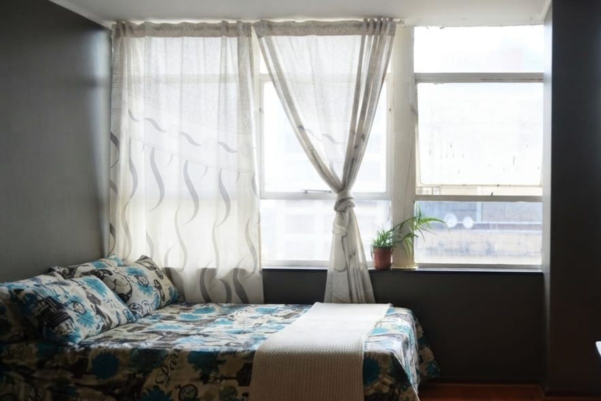 A bedroom featuring laminate flooring and a large window that provides natural light.