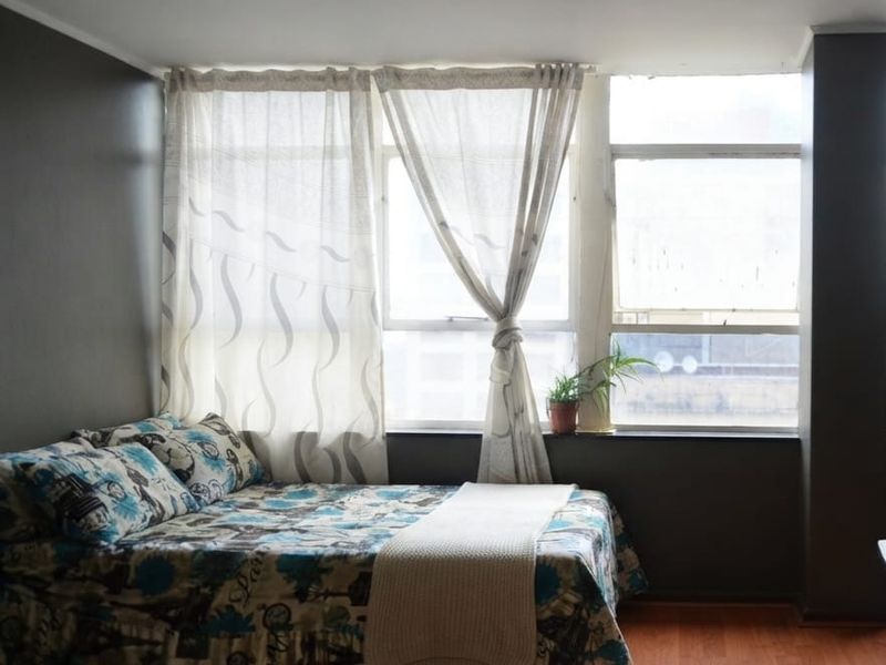 A bedroom featuring laminate flooring and a large window that provides natural light.