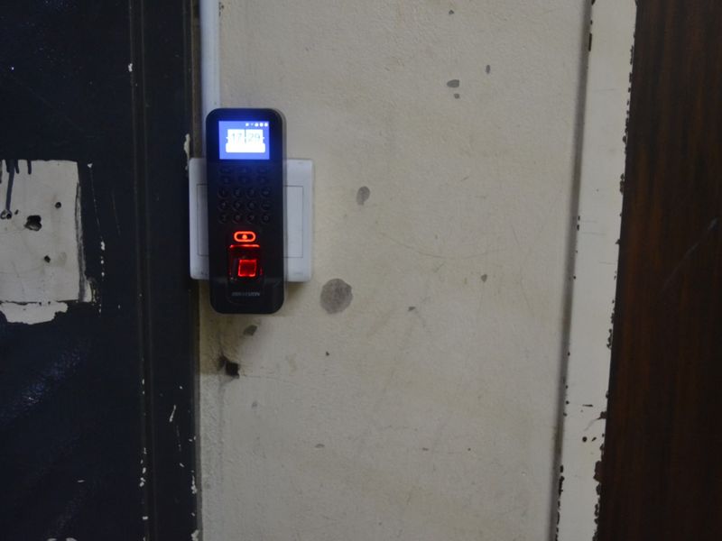 Close-up view of a wall-mounted biometric security access control system installed near the apartment entrance.