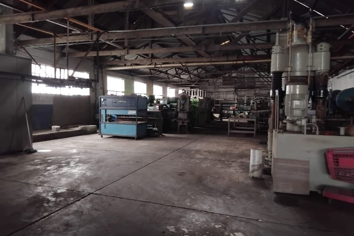Spacious industrial utility area featuring exposed timber roof trusses, concrete flooring, and large windows, suitable for manufacturing or warehouse operations.