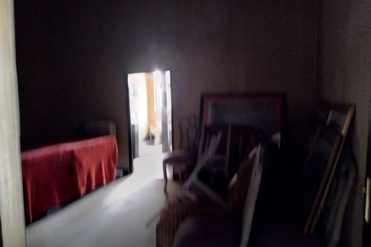 A dimly lit interior space showing a doorway leading to an adjacent room, with limited visibility of fixed architectural features.
