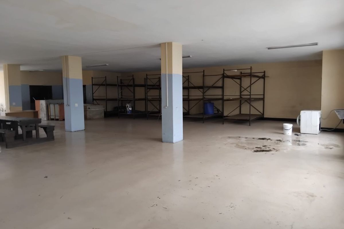 A large, open-plan commercial utility or storage space featuring structural columns, fluorescent lighting, and durable epoxy flooring, suitable for various business or industrial uses.