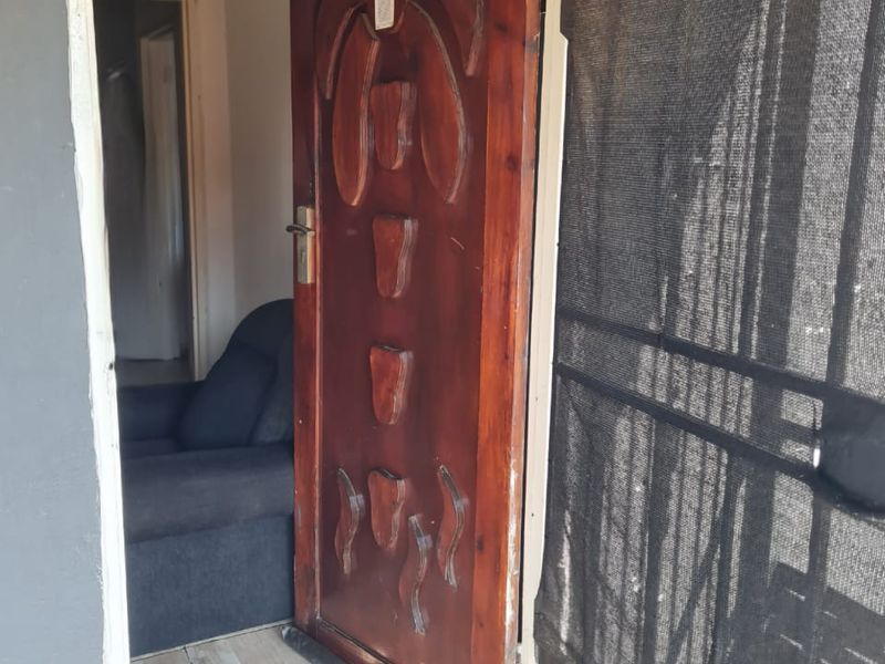 Entrance area featuring a decorative solid wood front door and security gate, leading into the main living space with tiled flooring.