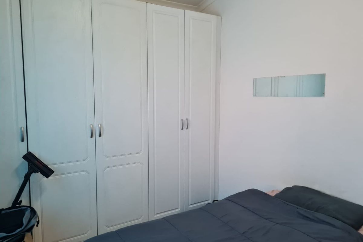 A bedroom featuring white built-in cupboards with classic panel detailing and simple hardware, providing ample storage space.