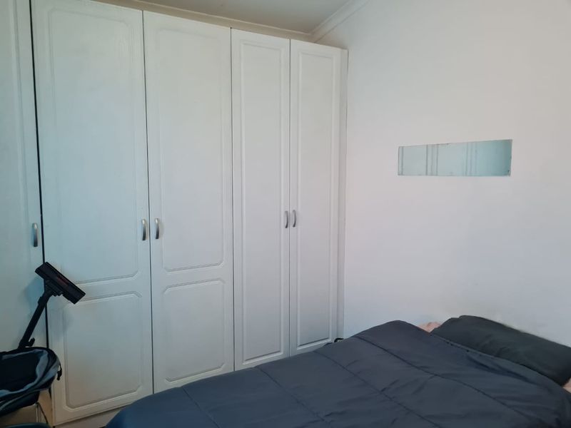 A bedroom featuring white built-in cupboards with classic panel detailing and simple hardware, providing ample storage space.