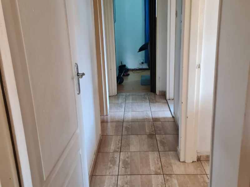 A functional hallway featuring tiled flooring and multiple internal door access points, connecting various rooms within the home.
