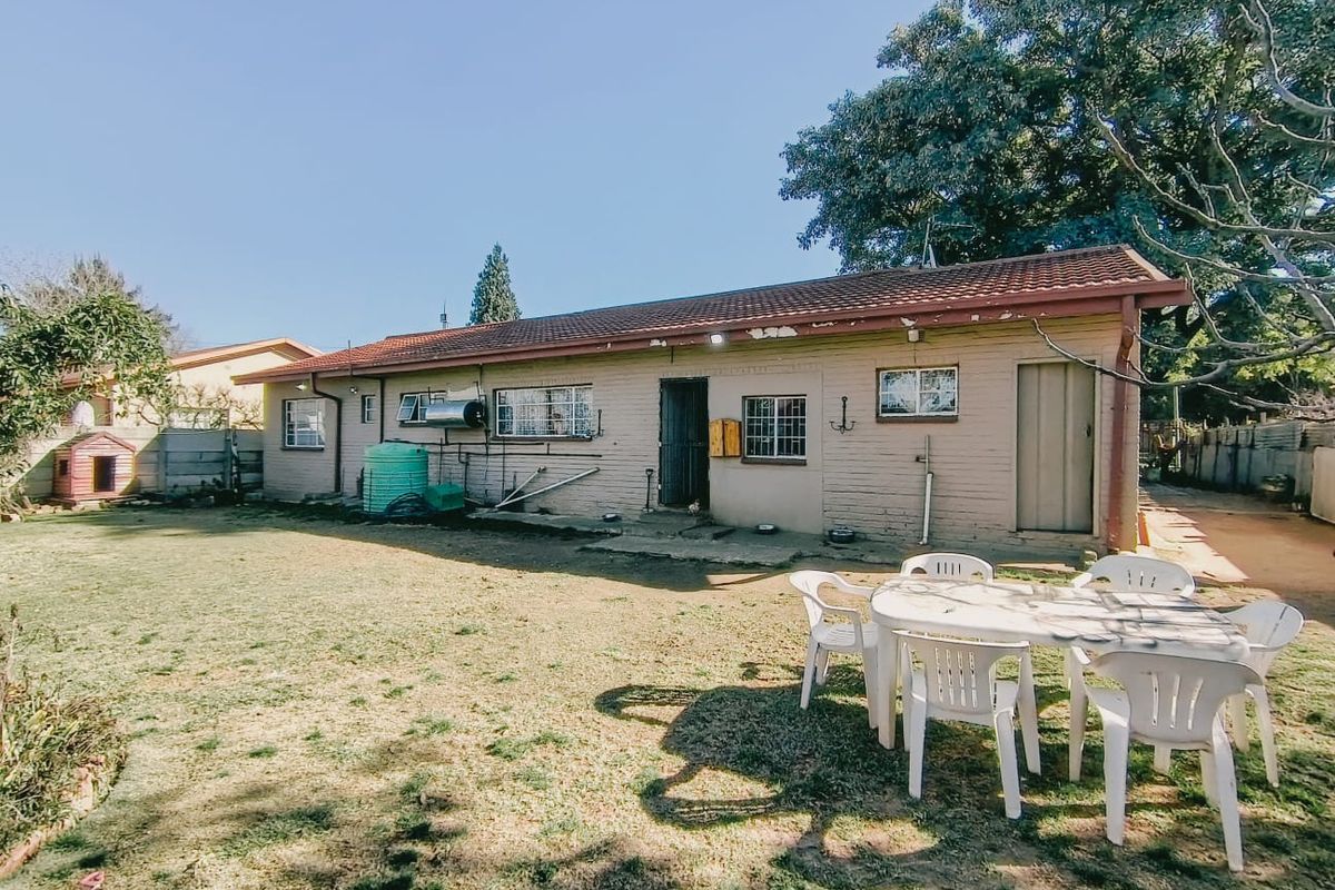 Rear view of the property featuring a brick facade, tiled roof, and an attached solar water heater system overlooking the backyard.