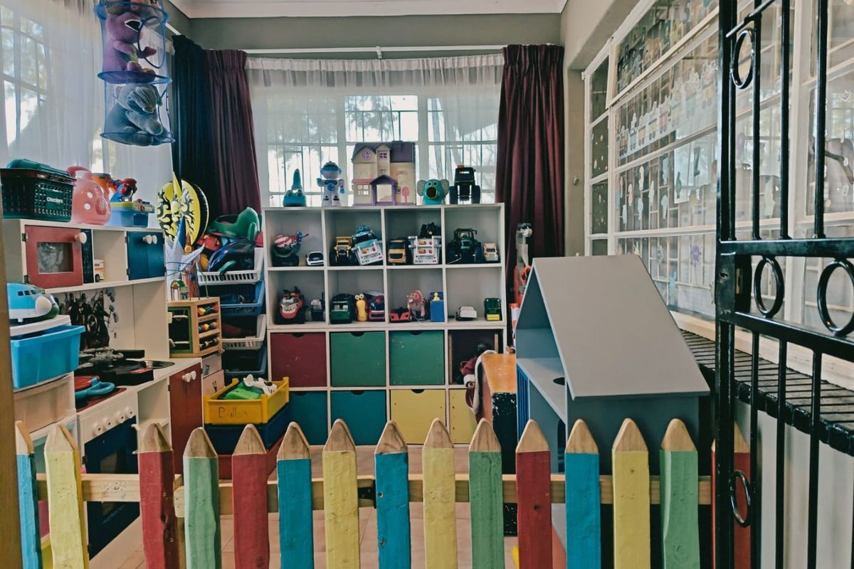 A multi-purpose living space featuring large windows and a security gate, currently utilized as a play area.