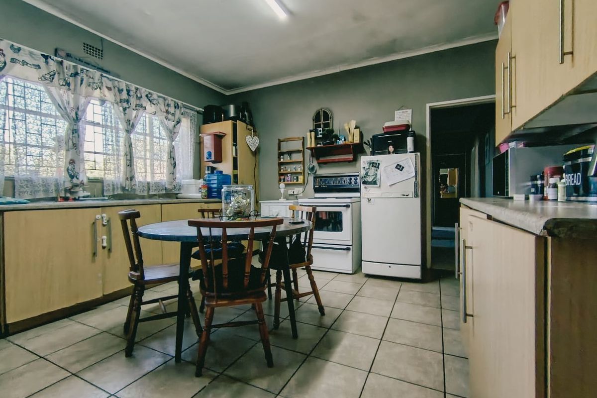 A functional kitchen featuring laminate cabinetry, tiled flooring, and a freestanding stove, with potential for cosmetic updates to modernize the space.
