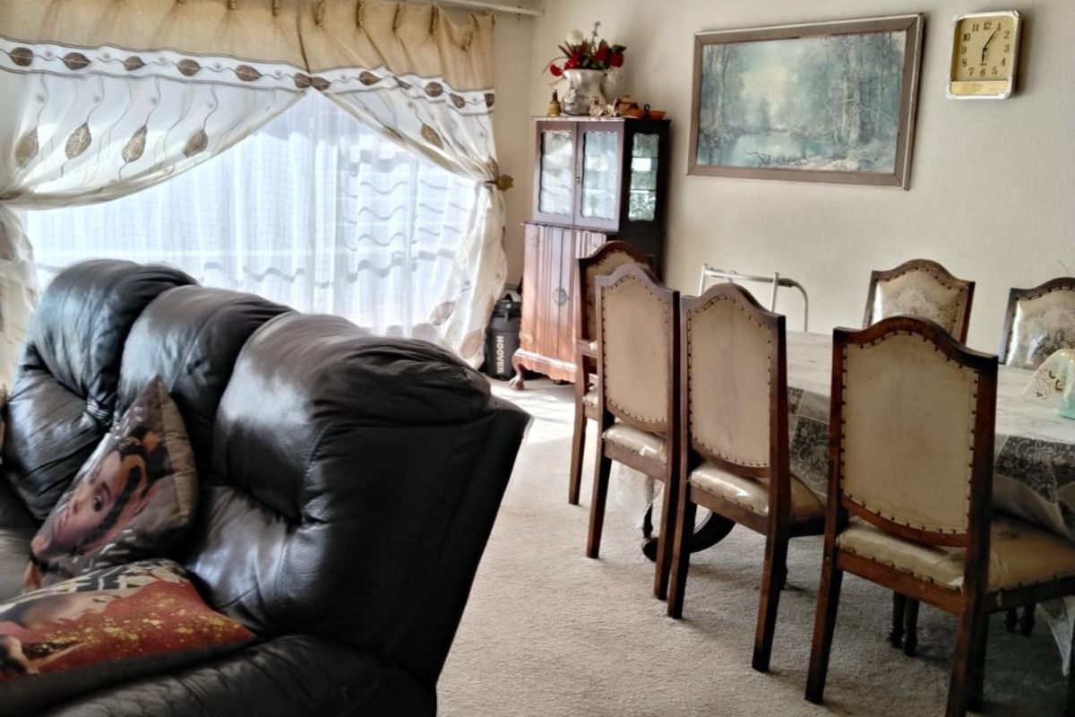 Open plan living and dining area featuring carpeted flooring and a ceiling fan, offering a functional space with potential for modernization.