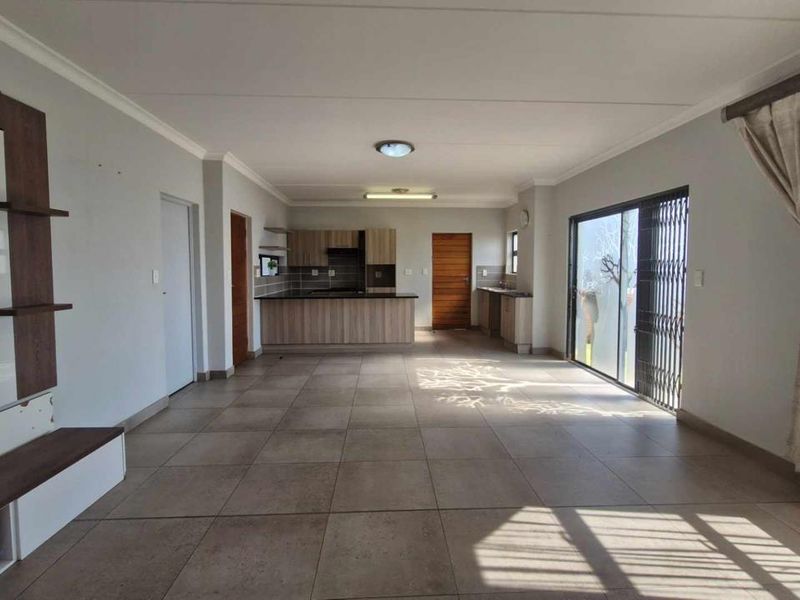 Spacious open-plan living and kitchen area featuring large floor tiles, modern cabinetry, and sliding doors leading to the exterior.