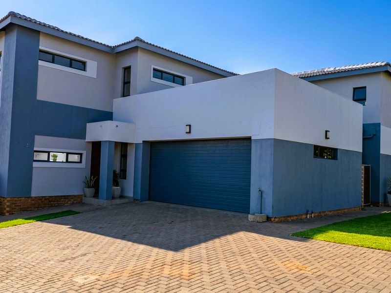 Modern double-story residential property featuring a paved driveway, double garage, and contemporary two-tone exterior facade.
