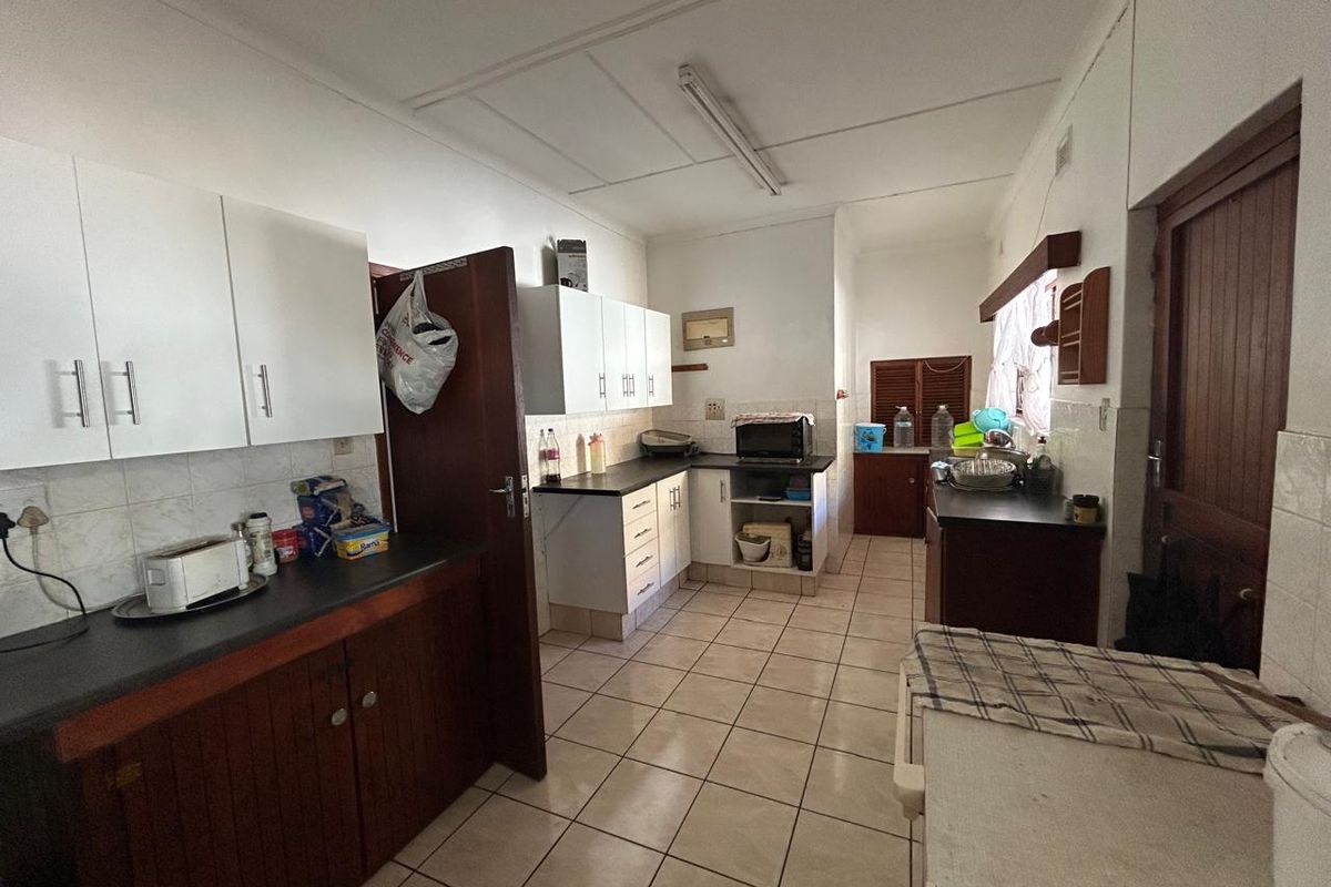 A functional kitchen featuring laminate countertops, ample built-in cabinetry, and ceramic floor tiles, offering a practical layout with potential for modern updates.