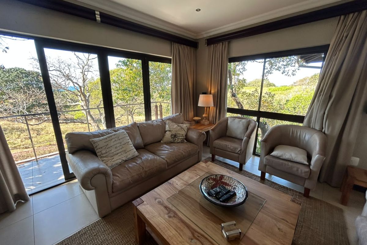 A bright living room featuring large sliding glass doors that provide ample natural light and views of the surrounding greenery.