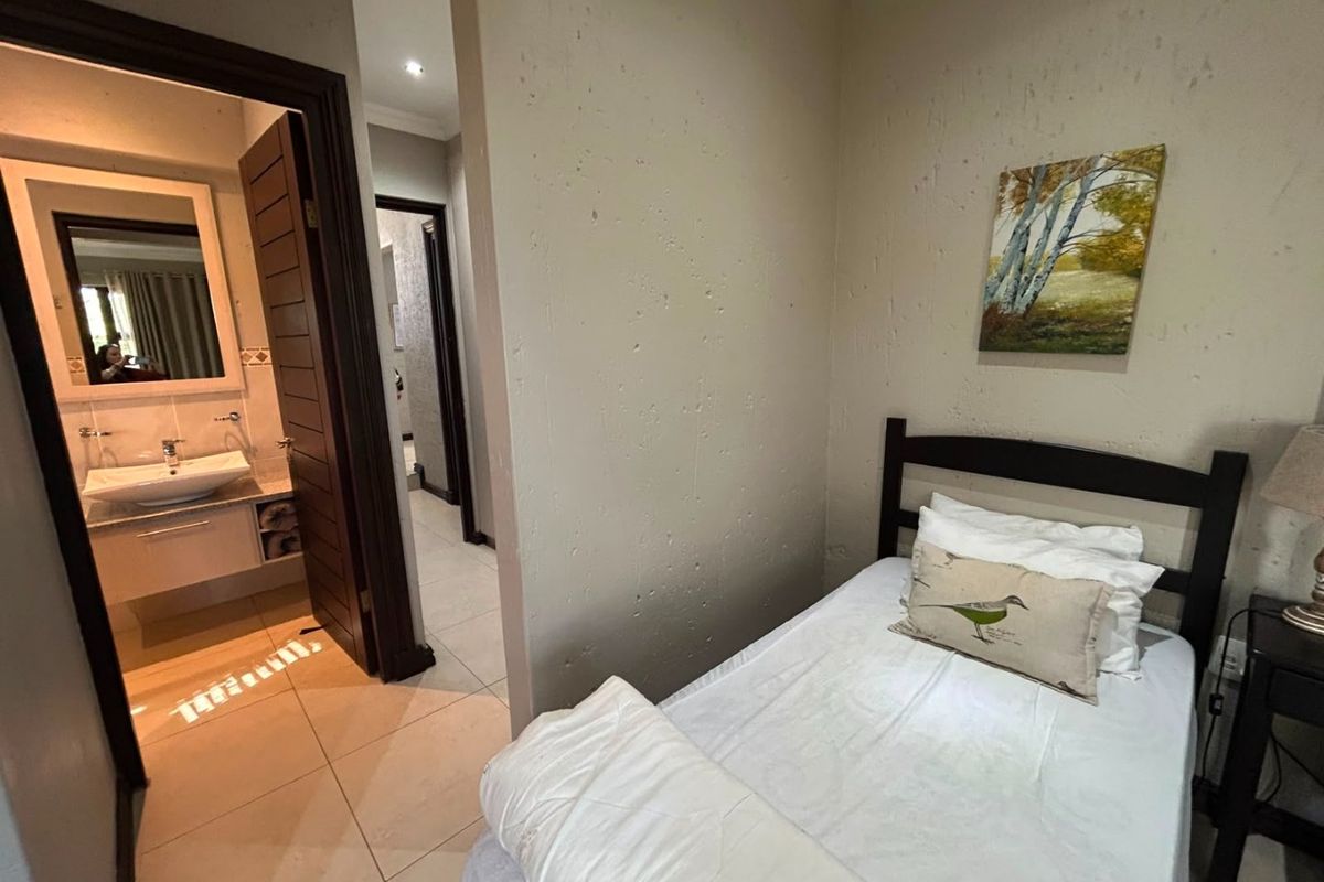 A bedroom featuring tiled flooring and an adjoining en-suite bathroom with a modern vanity and basin.