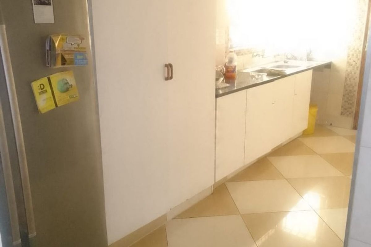 A dated kitchen featuring built-in cabinetry, a sink, and tiled flooring, requiring modernization to improve functionality and aesthetic appeal.