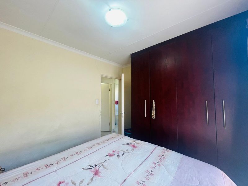 A bedroom featuring dark wood built-in cupboards and neutral wall finishes, providing functional storage space.