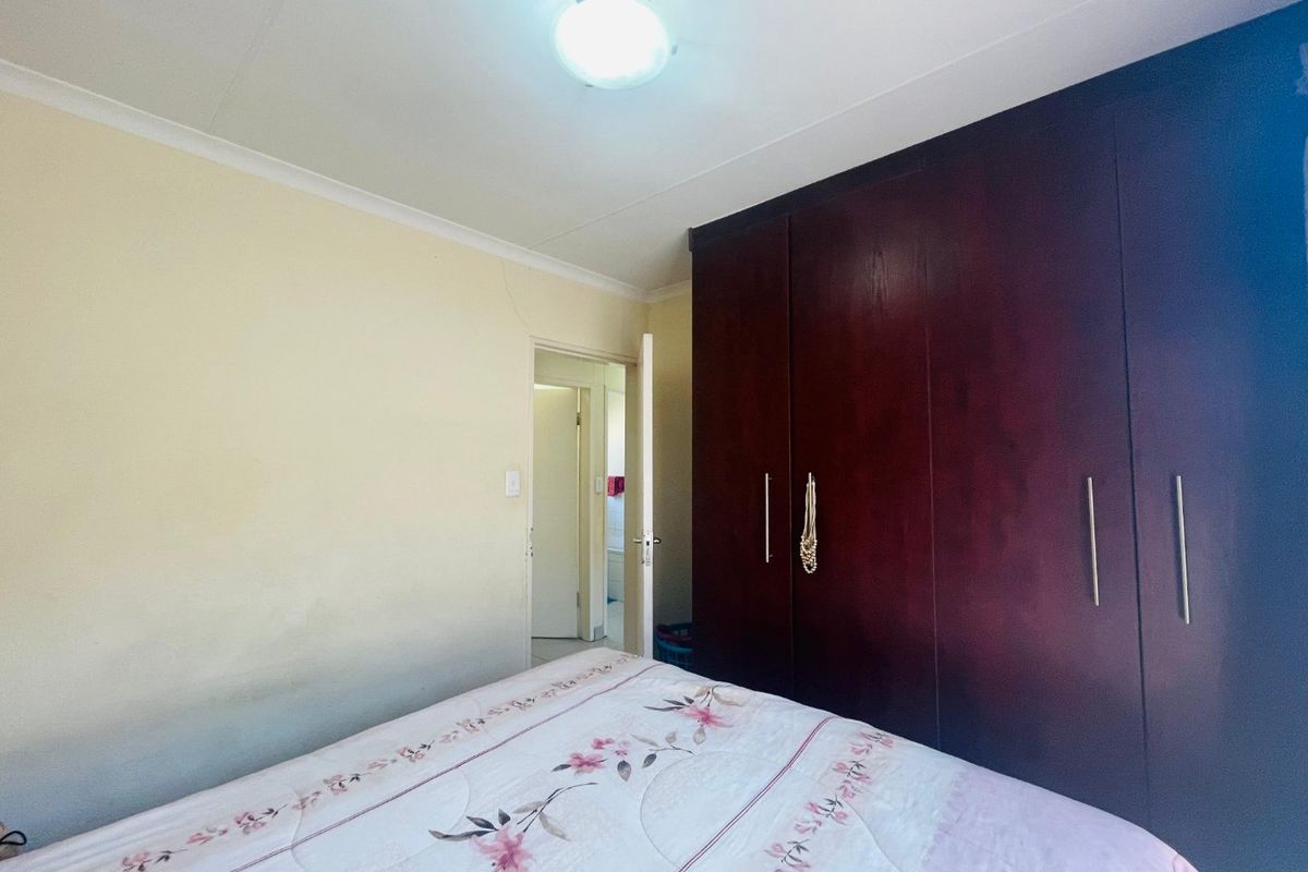 A bedroom featuring dark wood built-in cupboards and neutral wall finishes, providing functional storage space.