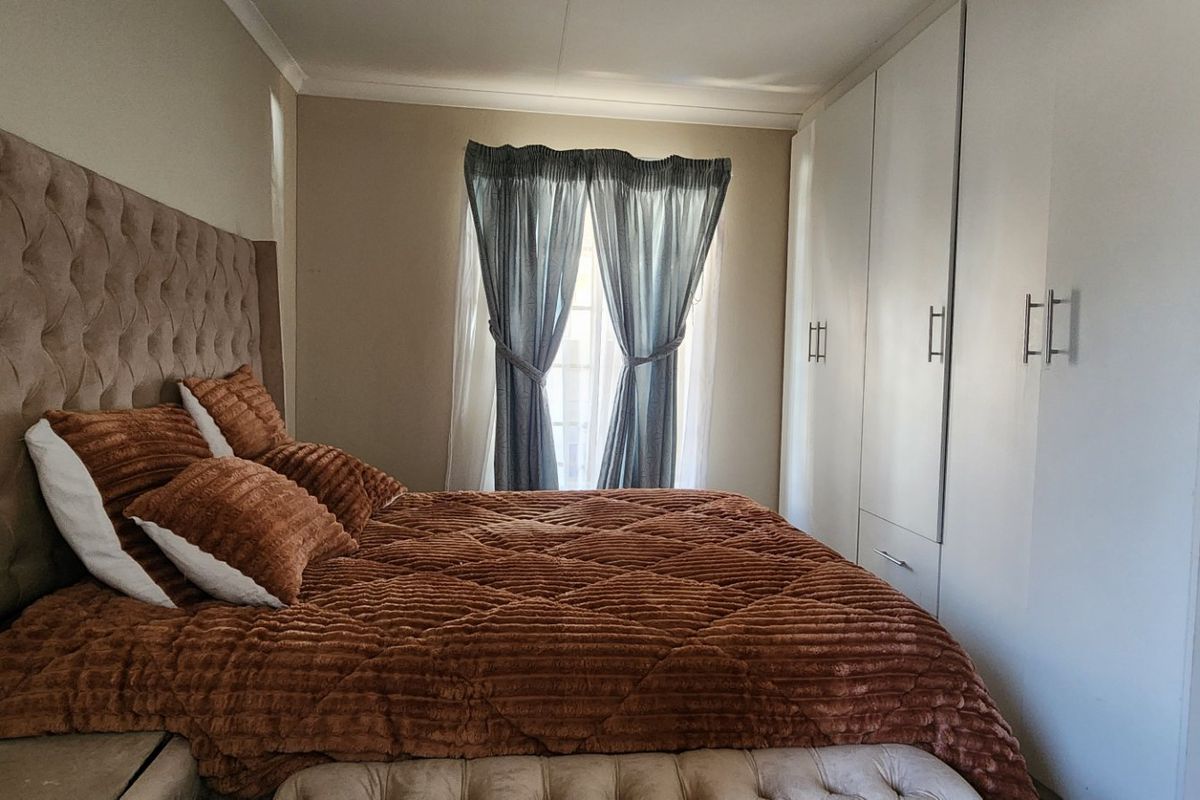 A well-maintained bedroom featuring ample built-in cupboard storage and neutral wall finishes, providing a comfortable and functional living space.